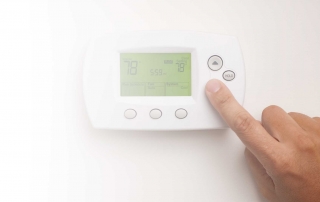 Picture of a hand adjusting a thermostat.