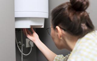 A woman inspecting her electric water heater